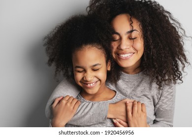 Happy african american mom and her cute little daughter smiling and embracing with eyes closed. - Powered by Shutterstock