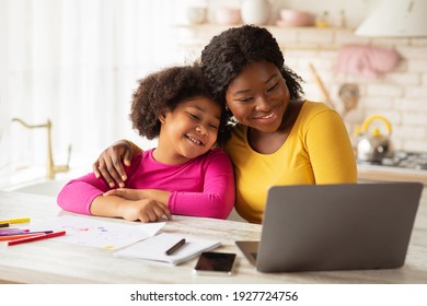 Happy African American Mom And Her Cute Little Daughter Using Laptop Together In Kitchen, Black Family Having Fun At Home, Embracing And Watching Cartoons Or Kids Development Videos Online, Free Space