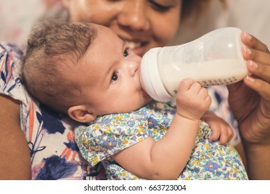 Happy African American Mother Bottle Feeding Her Mixed Race Baby Daughter