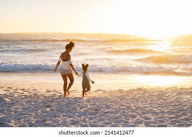 Happy african american mother with cute little girl at beach walking towards the sea. Black family walking towards ocean on beach during sunset with copy space. Mother and child running barefoot. - Powered by Shutterstock