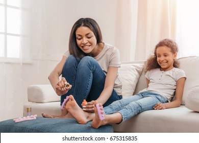 Happy african american mother and daughter doing pedicure together at home - Powered by Shutterstock