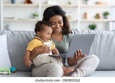 Happy African American Mother And Infant Baby Using Laptop At Home, Smiling Black Mom And Cute Toddler Child Watching Online Videos On Computer While Relaxing On Couch In Living Room, Closeup