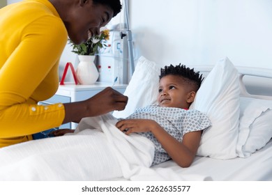 Happy african american mother sitting with son patient in hospital bed, smiling with copy space. Hospital, medical and healthcare services. - Powered by Shutterstock