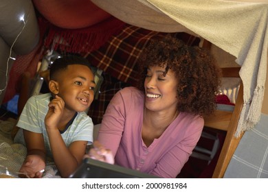 Happy African American Mother With Son At Home, Lying In Blanket Fort And Using Tablet. Family Enjoying Quality Free Time Together.