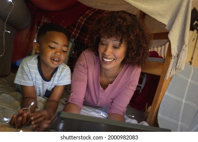 Happy African American Mother With Son At Home, Lying In Blanket Fort And Using Tablet. Family Enjoying Quality Free Time Together.