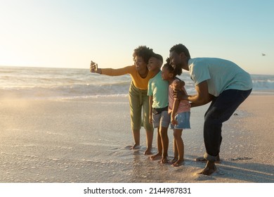 Happy African American Mother Taking Selfie With Family On Shore At Beach During Sunset. Unaltered, Family, Lifestyle, Togetherness, Technology And Holiday Concept.