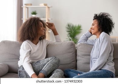 Happy African American Mother And Teen Daughter Having Pleasant Conversation, Laughing, Chatting At Home, Smiling Black Mum And Excited Teenage Girl Having Fun Together, Family Weekend