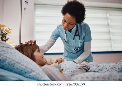 Happy African American nurse communicating with a child who is recovering at hospital ward. - Powered by Shutterstock