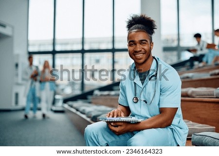Happy African American nursing student studying at medical university and looking at camera. 