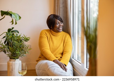 happy african american old woman sitting by the window at home. enjoying retirement - Powered by Shutterstock