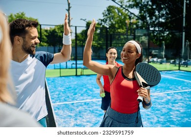 Happy African American paddle tennis player giving high-five to her rival after playing mixed doubles match, - Powered by Shutterstock