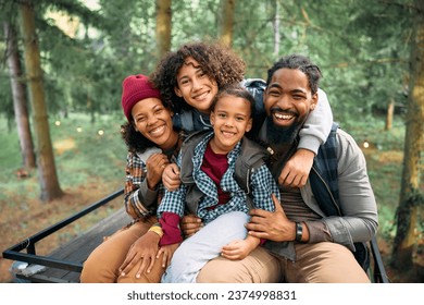 Happy African American parents with kids enjoying in camping at trailer park in the woods and looking at camera.  - Powered by Shutterstock