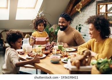 Happy African American parents and their kids enjoying in family meal at dining table. 
