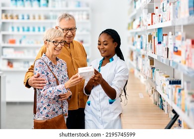 Happy African American pharmacist advising senior couple in choosing vitamins in drugstore.  - Powered by Shutterstock