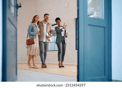 Happy African American real estate agent showing a house for sale to a couple interested in buying it. Copy space. - Powered by Shutterstock