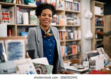 Happy African American saleswoman at bookstore checkout looking at camera. 