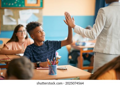 Happy African American schoolboy giving high-five to his teacher during  class in the classroom. - Powered by Shutterstock