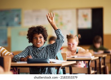 Happy African American schoolboy raising arm to answer a question in the classroom. - Powered by Shutterstock