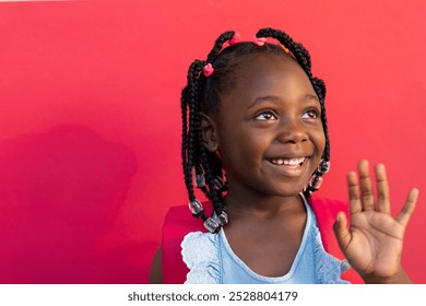 Happy african american schoolgirl waving hand over pink background at elementary school. Education, childhood, development, learning and school, unaltered. - Powered by Shutterstock