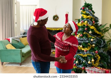 Happy african american senior couple in santa hats dancing at home at christmas time. retirement lifestyle and christmas festivities, celebrating at home. - Powered by Shutterstock