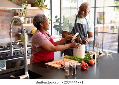 Happy african american senior couple cooking together in kitchen. retirement lifestyle, leisure and spending time at home. - Powered by Shutterstock