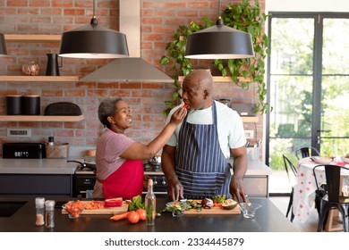 Happy african american senior couple cooking together in kitchen. retirement lifestyle, leisure and spending time at home. - Powered by Shutterstock