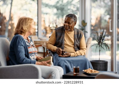 Happy African American senior man and his female friend communicating while drinking tea and relaxing in residential care home.  - Powered by Shutterstock