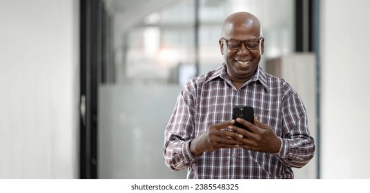 Happy African American Senior Man checks cell phone standing at home office. - Powered by Shutterstock