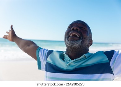 Happy African American Senior Retired Man With Eyes Closed And Arms Outstretched At Beach. Unaltered, Active Lifestyle, Enjoyment And Holiday Concept.