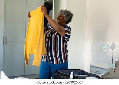 Happy African American Senior Woman Preparing Clothes For Packing. Travel Preparation During Covid 19 Pandemic.