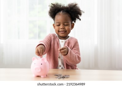 Happy African American small girl kid putting money into the piggybank. Little girl inserting a coin in a piggy bank. Kid investment for future concept  - Shutterstock ID 2192364989