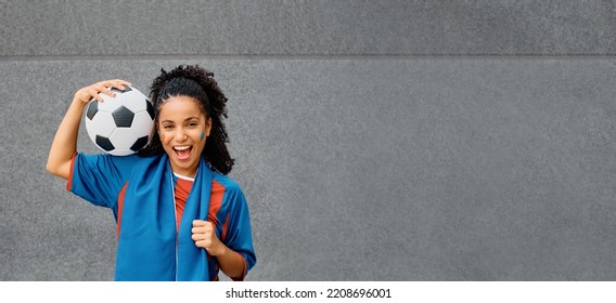 Happy African American Soccer Fan Holding Ball While Wearing Jersey Of Her Favorite Team And Looking At Camera.  Copy Space.