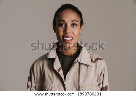 Happy african american soldier woman smiling and looking at camera isolated over grey wall