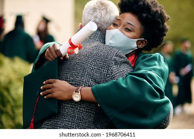 Happy African American Student With Face Mask Embracing Her Father On Her Graduation Day.