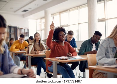 Happy African American student raising her hand to ask a question during lecture in the classroom. 