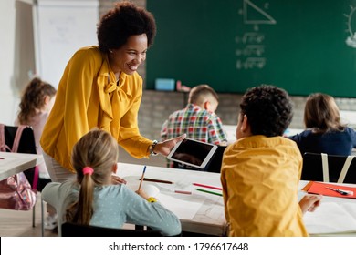 Happy African American teacher and school kids using touchpad on a class at the school.  - Powered by Shutterstock