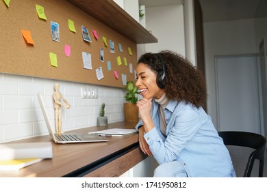 Happy African American Teen Girl Student Worker Wear Headphones Video Conference Calling Online On Laptop Computer Laughing At Home Office. Elearning Zoom App Video Call, Distance Videoconference.