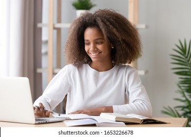 Happy african american teen high school student studying with laptop books doing online research homework assignment, smiling black teenage girl using computer for children online education concept