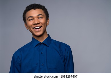 Happy African American teenager in denim shirt. Isolated on a gray background. Studio portrait. Transitional age concept.