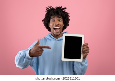 Happy African American Teenager Pointing At Tablet Computer With Mockup For Website Or App On Screen, Pink Studio Background. Joyful Black Teen Showing Touch Pad With Space For Your Ad