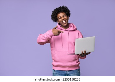 Happy African American teenager student boy holding device pointing at laptop computer technology advertising remote learning, online webinars, training courses isolated on light purple background. - Powered by Shutterstock