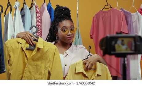 Happy african american trendy girl vlogger filming live fashion vlog streaming showing stylish clothes items isolated on background. Fashion influencer. Try-on haul. - Powered by Shutterstock