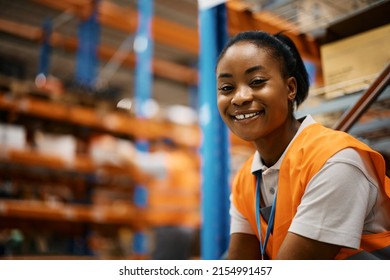 Happy African American Warehouse Worker On A Break At Storage Compartment Looking At Camera.