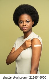 Happy African American Woman With Adhesive Plaster On Shoulder After Getting Coronavirus Vaccine Look At Camera. Young Vaccinated Black Girl And Covid-19 Vaccination Injection. Immunization And Health