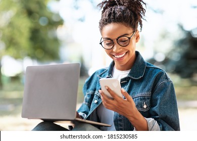 Happy African American Woman With Cellphone Texting Working On Laptop Sitting Outside. Good News Concept - Shutterstock ID 1815230585