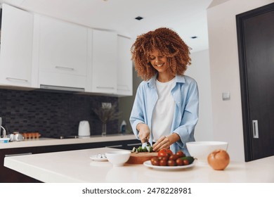 Happy African American woman cooking healthy salad in home kitchen with fresh ingredients and utensils - Powered by Shutterstock