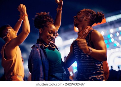 Happy African American woman dancing with her boyfriend during open air music concert at night. - Powered by Shutterstock