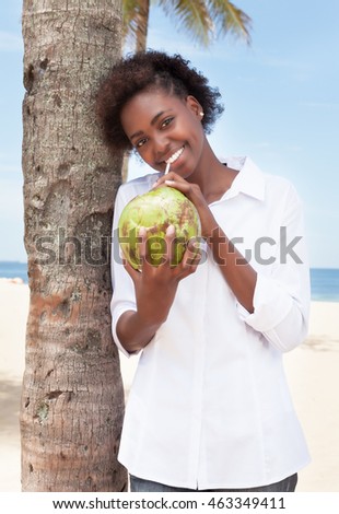 Happy african american woman drinking coconut water