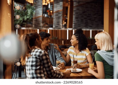 Happy African American woman having fun while communicating with group of her friends in a cafe.  - Powered by Shutterstock