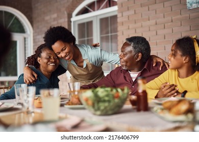 Happy African American woman and her senior parents embracing while having family lunch on patio.  - Powered by Shutterstock